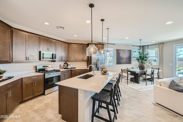 kitchen featuring visible vents, a breakfast bar, a sink, stainless steel appliances, and light countertops