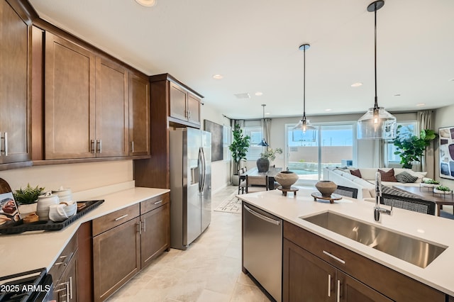 kitchen featuring a sink, stainless steel appliances, pendant lighting, and light countertops