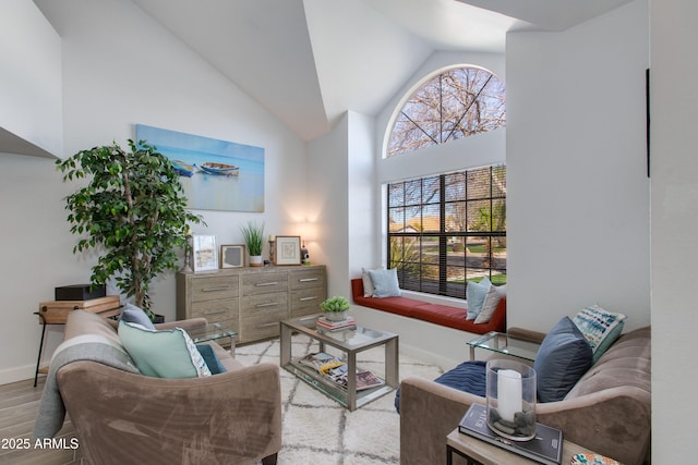 living room with high vaulted ceiling, a wealth of natural light, and light wood-type flooring