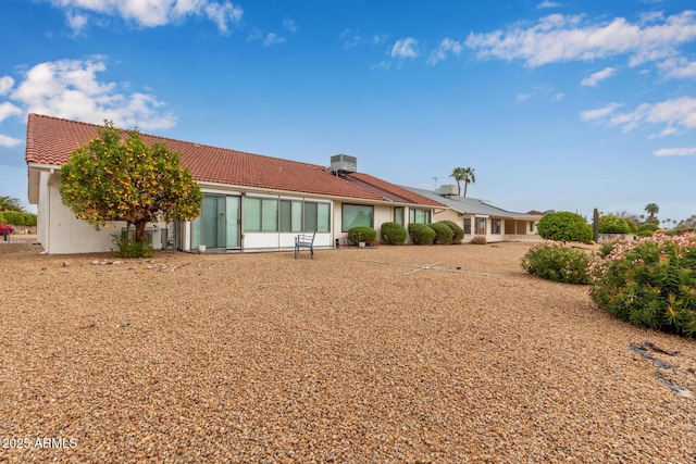 back of property featuring stucco siding and a tiled roof