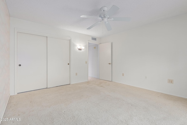 unfurnished bedroom featuring a closet, visible vents, carpet floors, and ceiling fan