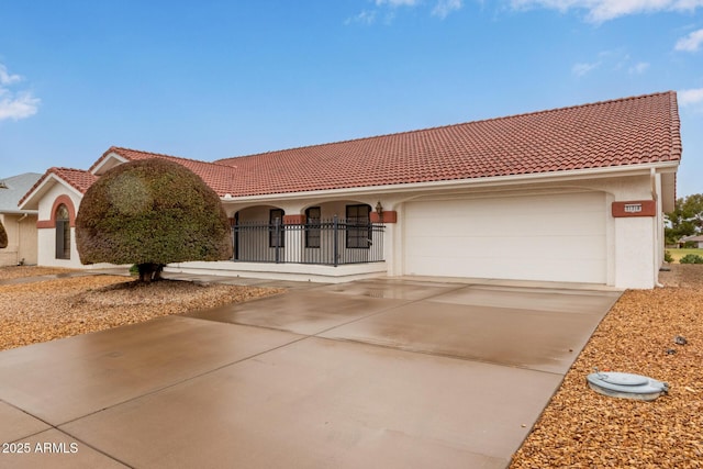 mediterranean / spanish house with a tiled roof, stucco siding, an attached garage, and concrete driveway