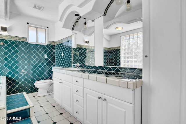 538 S Macdonald, Mesa, AZ 85210 - bathroom with tile patterned flooring, tile walls, vanity, wainscoting, and plenty of natural light