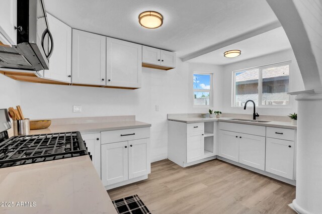538 S Macdonald, Mesa, AZ 85210 - kitchen with stainless steel microwave, light countertops, white cabinetry, light wood-style flooring, and arched walkways