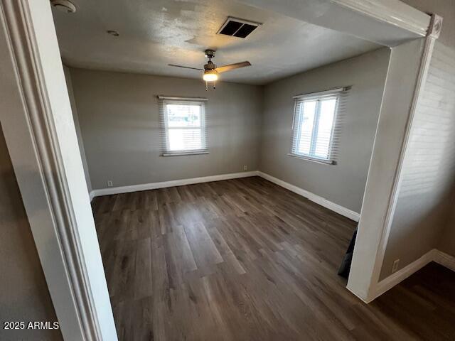 unfurnished room featuring dark wood-type flooring, a wealth of natural light, and ceiling fan