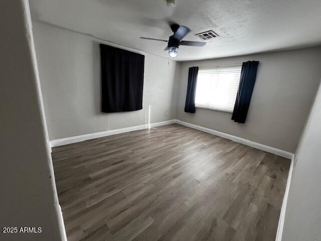 unfurnished room with a textured ceiling, dark hardwood / wood-style floors, and ceiling fan