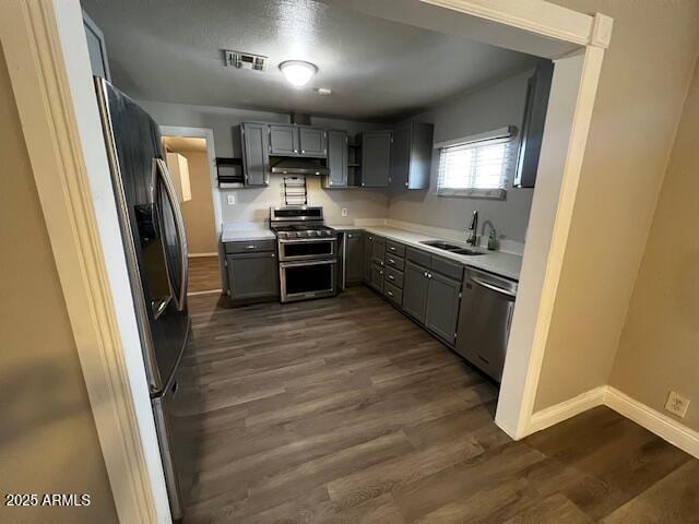 kitchen featuring stainless steel appliances, dark hardwood / wood-style floors, gray cabinets, and sink