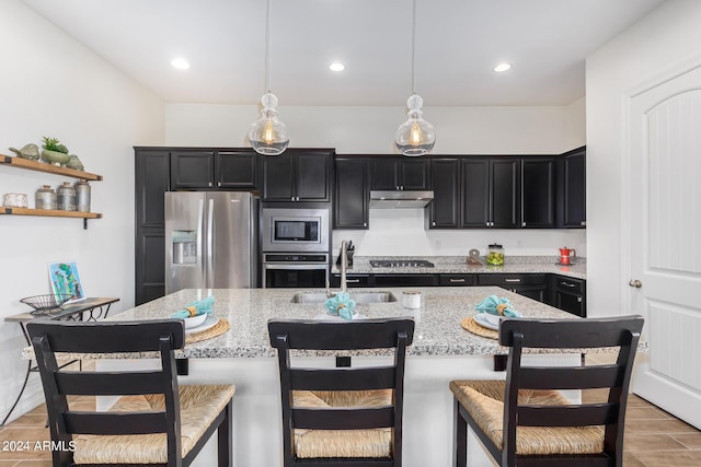 kitchen with appliances with stainless steel finishes, a kitchen bar, sink, and hanging light fixtures