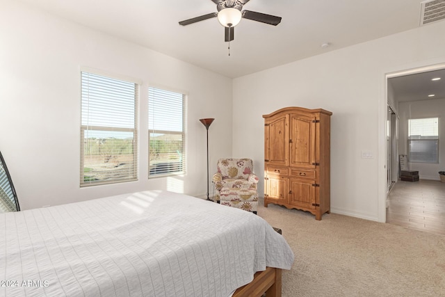 bedroom with ceiling fan, light colored carpet, and multiple windows