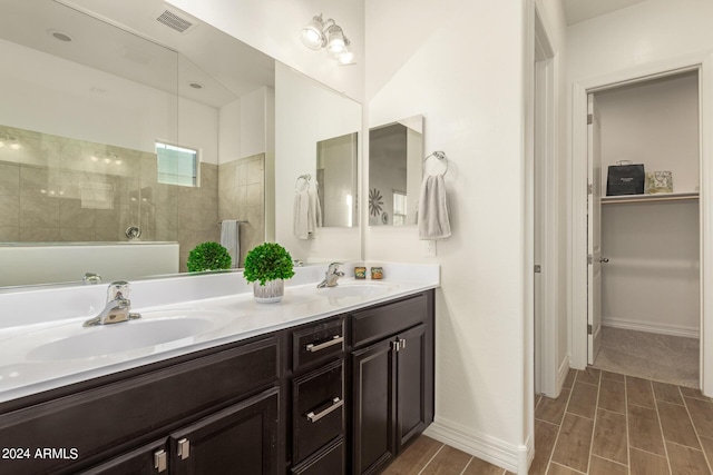 bathroom featuring tiled shower and vanity