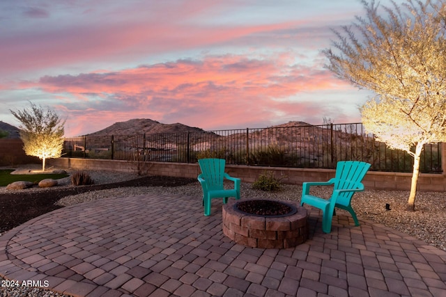 patio terrace at dusk featuring a mountain view and an outdoor fire pit