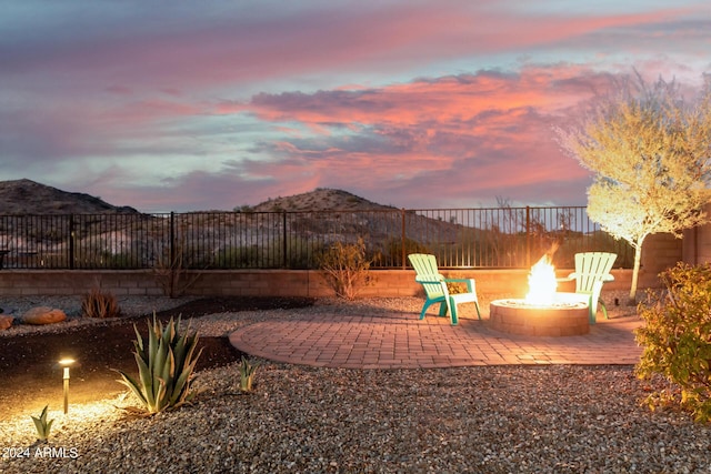 patio terrace at dusk featuring a mountain view and a fire pit