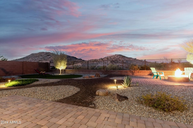 yard at dusk featuring a mountain view, a patio area, and a fire pit