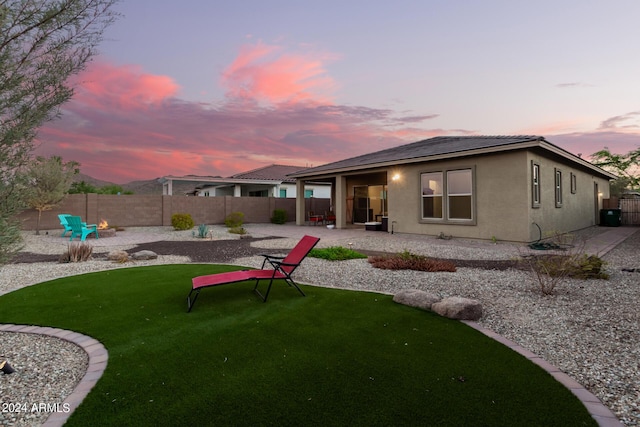 back house at dusk with a yard and a patio area