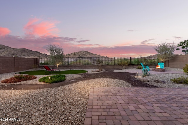 patio terrace at dusk featuring a mountain view and an outdoor fire pit