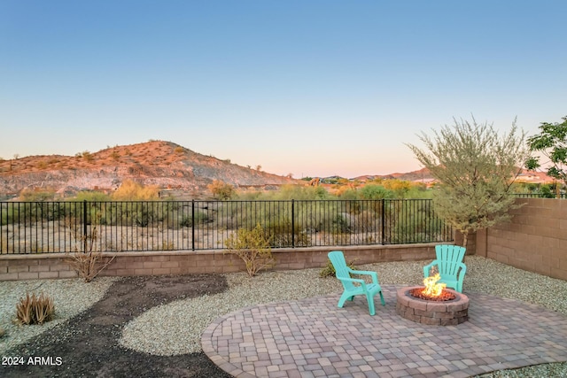 patio terrace at dusk featuring an outdoor fire pit and a mountain view