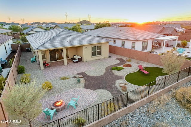 back house at dusk with a patio area and an outdoor fire pit