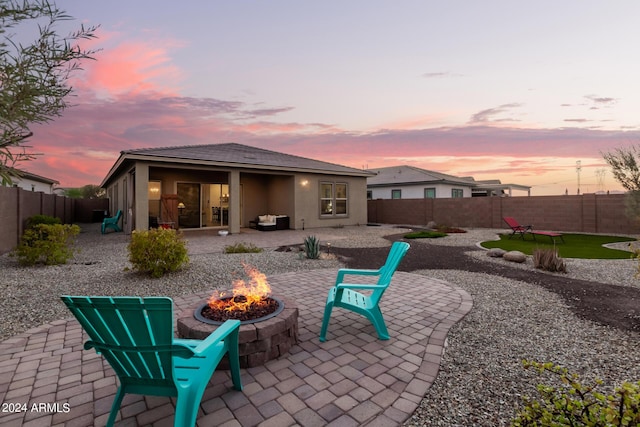 back house at dusk with a fire pit and a patio area