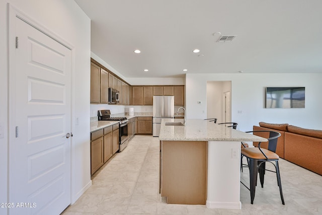 17819 W Georgia Ave, Litchfield Park, AZ 85340 - kitchen with stainless steel appliances, open floor plan, light stone countertops, a kitchen island with sink, and recessed lighting