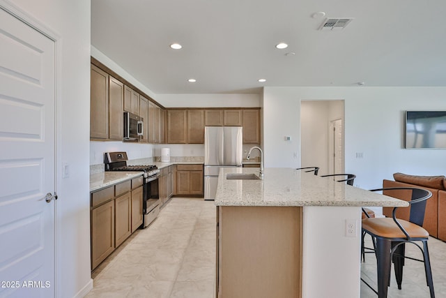 17819 W Georgia Ave, Litchfield Park, AZ 85340 - kitchen with stainless steel appliances, a kitchen island with sink, a breakfast bar area, recessed lighting, and light stone counters