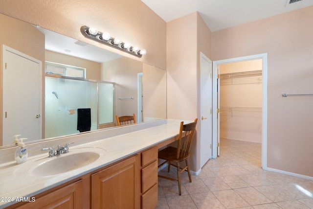 bathroom featuring tile patterned flooring, vanity, and walk in shower