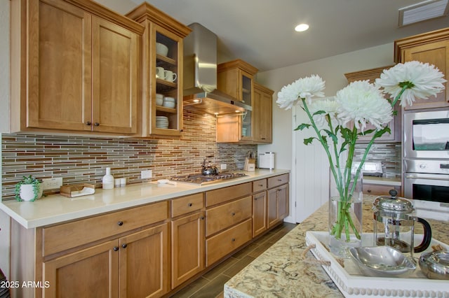 kitchen with decorative backsplash, wall chimney exhaust hood, stainless steel appliances, and light stone counters