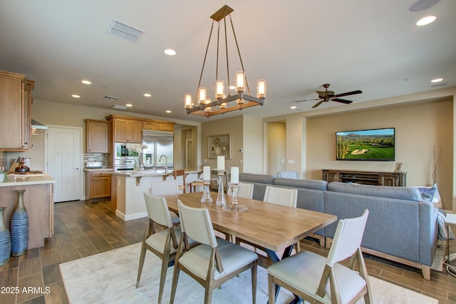 dining space featuring ceiling fan with notable chandelier and sink