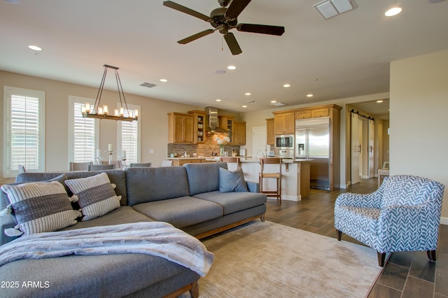 living room with ceiling fan with notable chandelier