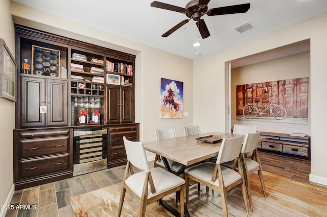 dining area featuring bar, ceiling fan, and beverage cooler