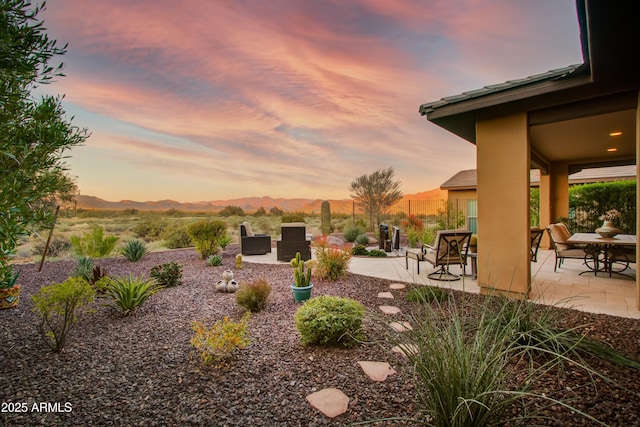 yard at dusk featuring a mountain view and a patio