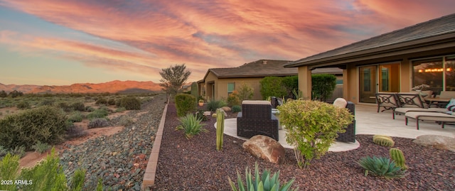 yard at dusk featuring a mountain view and a patio area