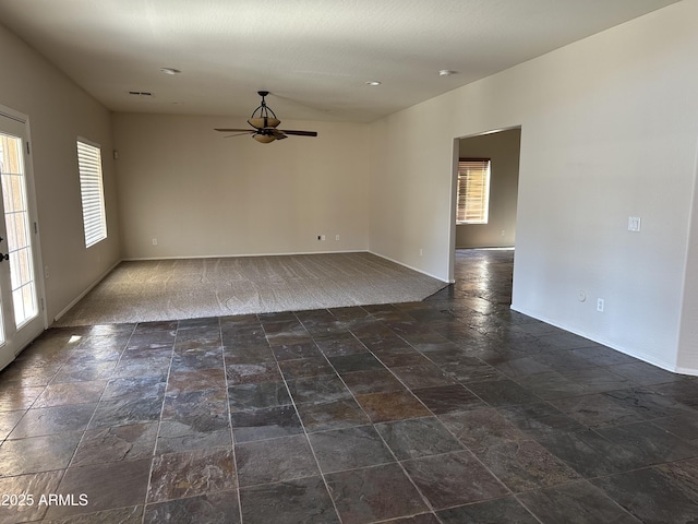 unfurnished room with ceiling fan and dark carpet