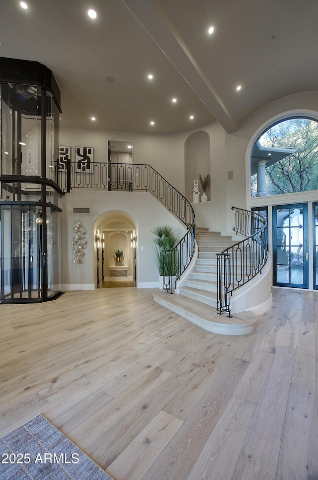 foyer with a towering ceiling and light hardwood / wood-style flooring