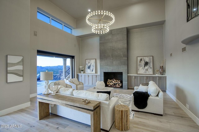 living room featuring a mountain view, a towering ceiling, a fireplace, and a chandelier