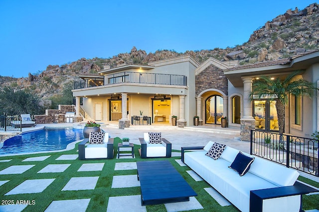 back of property featuring ceiling fan, a balcony, outdoor lounge area, and a patio area