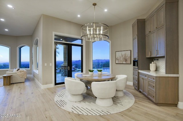 dining room with an inviting chandelier, a mountain view, french doors, and light wood-type flooring