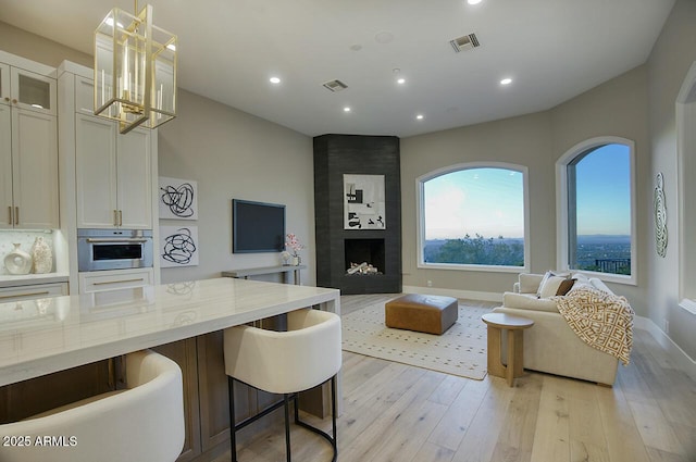 living room with a large fireplace and light hardwood / wood-style floors