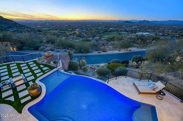 pool at dusk featuring a mountain view and a patio area