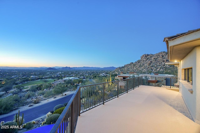 balcony at dusk featuring a mountain view