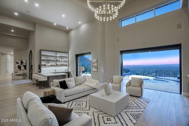 living room featuring an inviting chandelier, light hardwood / wood-style floors, and a high ceiling