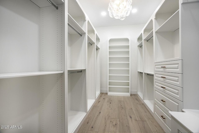 walk in closet featuring a notable chandelier and light wood-type flooring