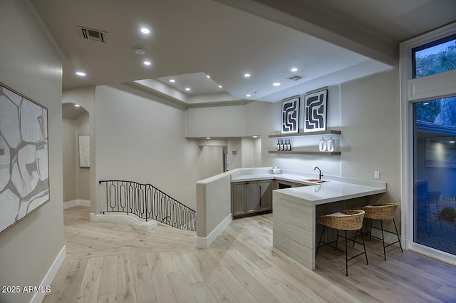 kitchen with light hardwood / wood-style flooring, sink, a breakfast bar area, and kitchen peninsula