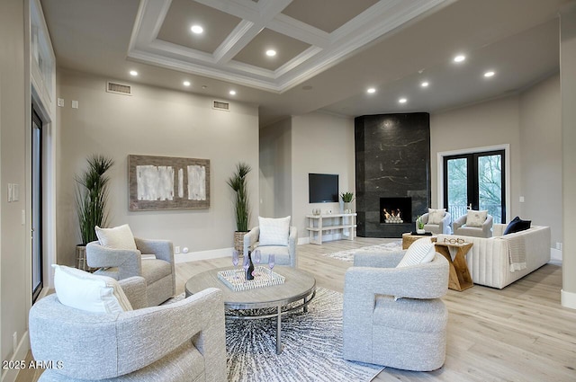 living room with coffered ceiling, beam ceiling, crown molding, light hardwood / wood-style flooring, and a fireplace