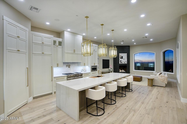 kitchen with a breakfast bar, decorative light fixtures, white cabinetry, light stone countertops, and a spacious island