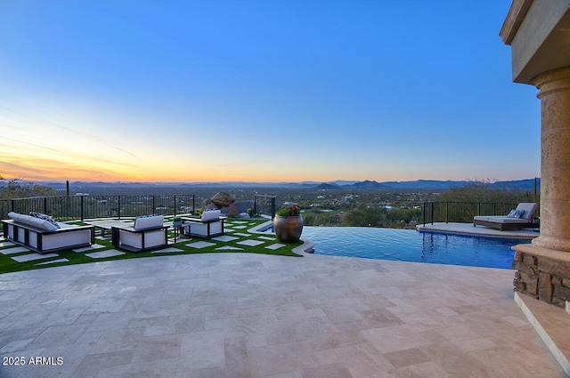 pool at dusk featuring a mountain view and a patio area