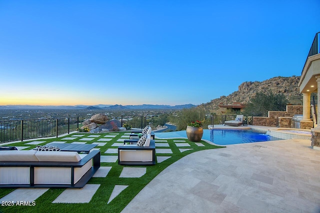 pool at dusk with a patio, outdoor lounge area, a yard, grilling area, and a mountain view