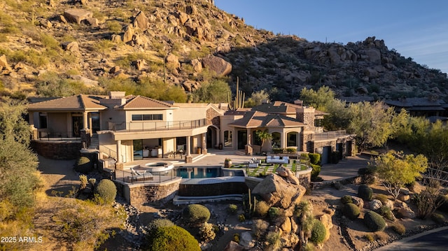 back of house featuring a mountain view, a pool with hot tub, and a patio area