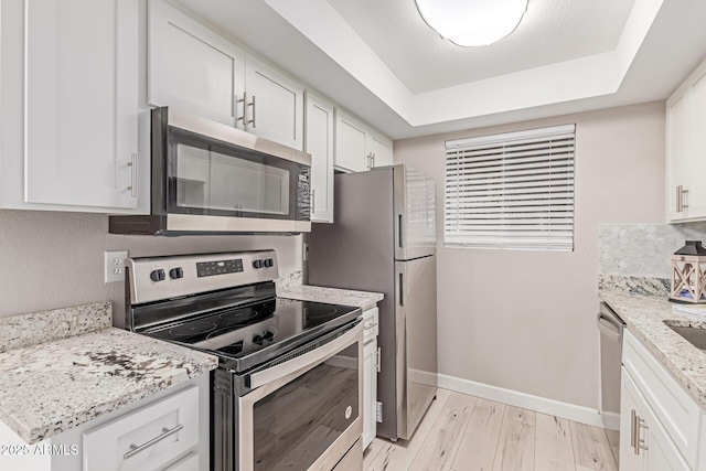 3119 W Cochise Dr Unit 111, Phoenix, AZ 85051 - kitchen featuring stainless steel appliances, white cabinetry, light wood-type flooring, a tray ceiling, and baseboards