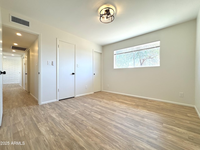 unfurnished bedroom with light wood-style floors, visible vents, and baseboards