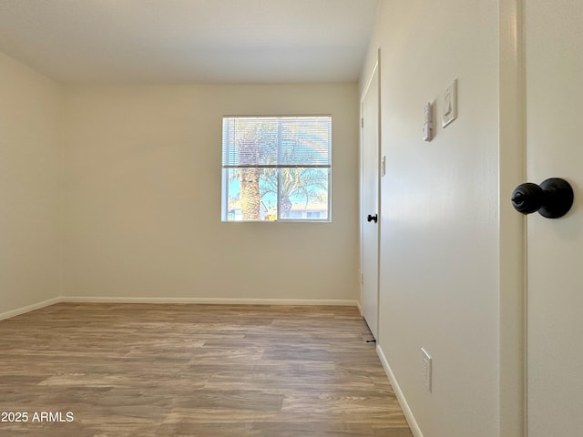 unfurnished room featuring baseboards and light wood-style floors